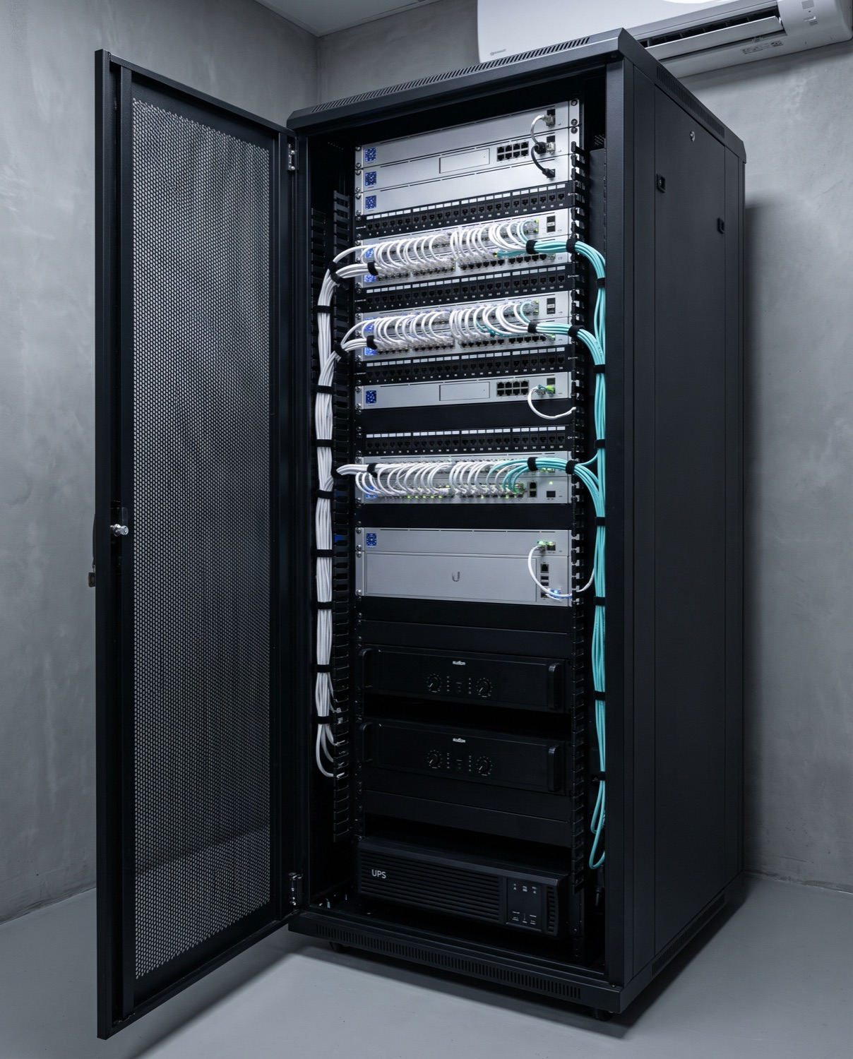 Network cabinet with UniFi switches, network storage and audio amplifiers, neatly patched